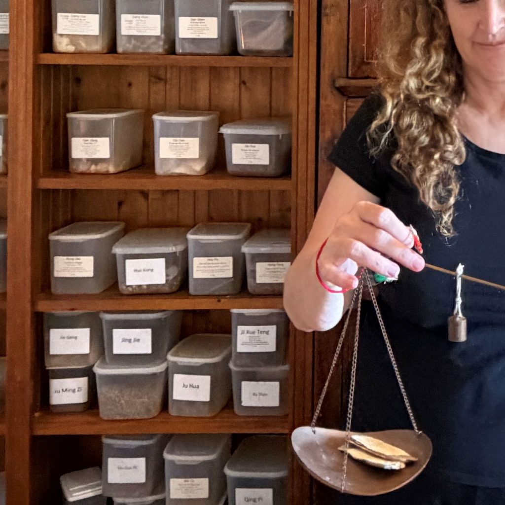 herbal dispensary in Redcliffe. Chinese medicine practitioner using traditional scales to weigh herbs for Chinese herbal formula
